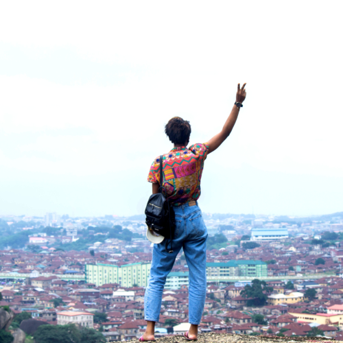 Nigerian lifestyle blogger Cassie Daves standing on the olumo rock in Abeokuta giving a peace sign