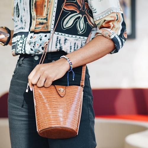 Cassie Daves wearing a vintage print shirt and brown mini bucket bag